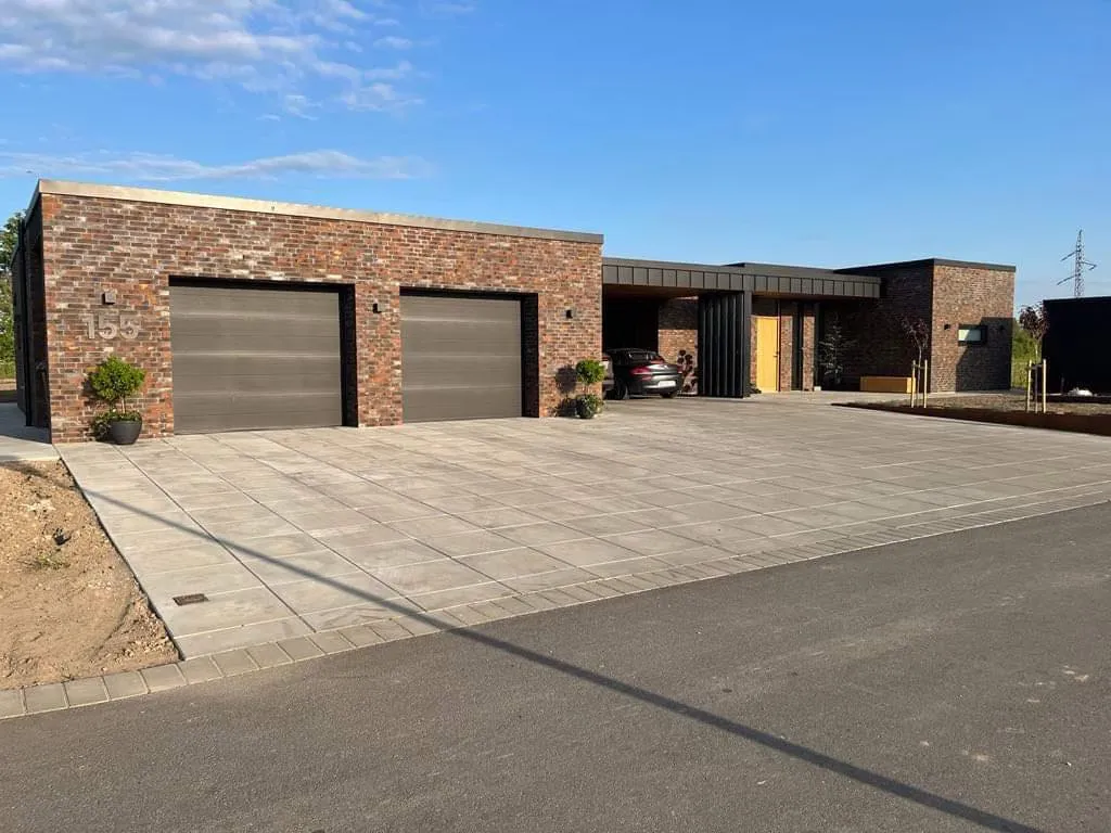 Nybygget hus i mørke mursten med dobbelt garage og flisebelagt indkørsel