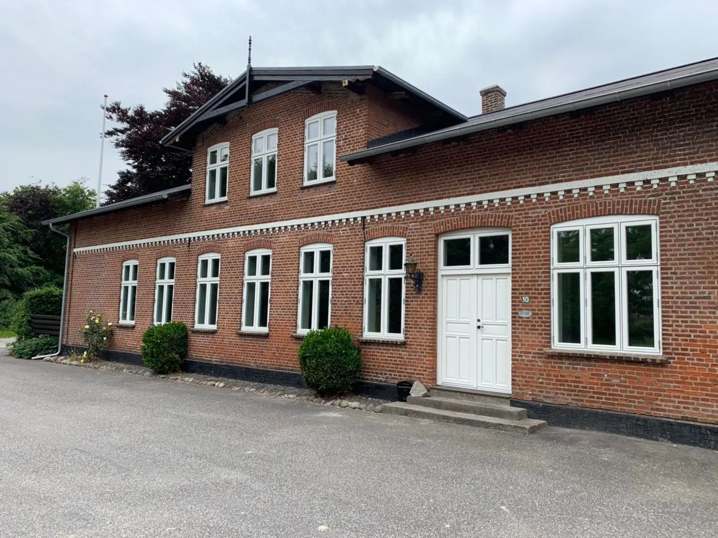 Ældre rødt murstenshus med nye hvide sprossevinduer og hvid dobbeltdør